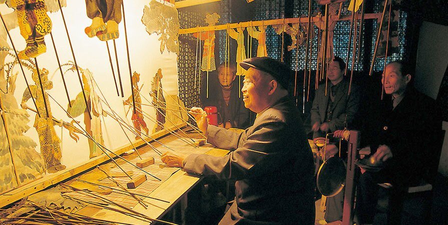 A folk articst is performing a shadow play show.